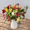 A bunch of mixed colour Cornish Alstroemeria with mixed colour British Tulips, arranged in a white jug vase.