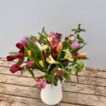 A bunch of mixed colour Cornish Alstroemeria with mixed colour British Tulips, arranged in a white jug vase.