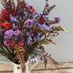 A close up of a jug of Agapanthus, Crocosmia & Verbena in a white tin jug.