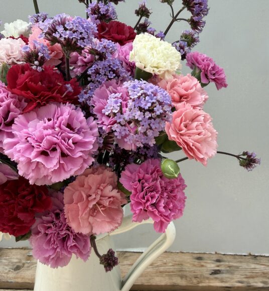 A vase full of Scented Pinks and Verbena in a white tin jug
