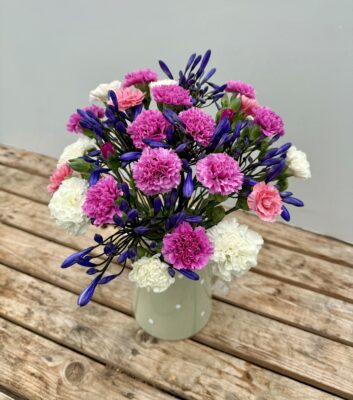 A green spotty jug of Scented Pinks and Agapanthus
