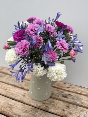 A green spotty jug of Scented Pinks and Agapanthus