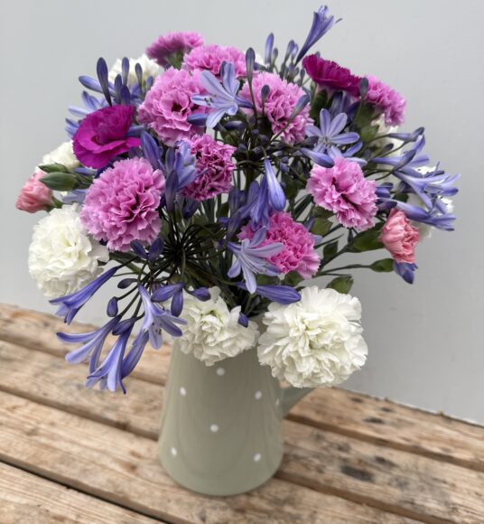 A green spotty jug of Scented Pinks and Agapanthus