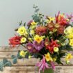 A mixed bouquet of Narcissi, Nerines and Chrysanthemums in a green tin jug